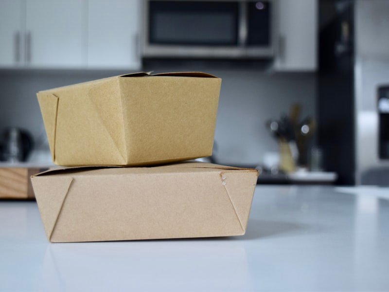 Kraft microwavable takeout containers stacked on a commercial kitchen counter